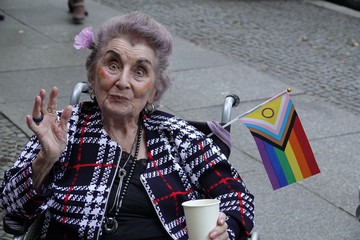 Eine Teilnehmerin im Rollstuhl mit einer LGBTQ-Fahne und einer Blume im Haar beim Besuch des Christopher Street Days in Berlin 2026 vom Immanuel Seniorenzentrum Schöneberg.