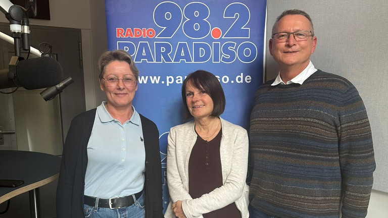 Nicole Oerder, Julia Nogli und Ralf Schäfer vor einem Aufsteller von Radio Paradiso - Immanuel Seniorenzentrum Schöneberg - Lebensort Vielefalt 