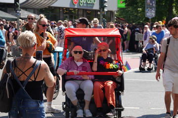 Eine rote Rikscha mit zwei Fahrgästen inmitten einer Menschenmenge beim Besuch des Christopher Street Days in Berlin 2026 vom Immanuel Seniorenzentrum Schöneberg.